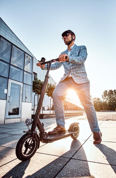 low-angle-photo-of-smart-elegant-man-in-sunglasses-and-helmet-which-is-driving-his-electrical-scooter